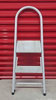 Front view of folded 2-step ladder showing steps, handrail and rubber feet