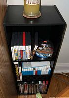 Front view of black 3-shelf unit showing DVDs, DS cases, RC toy
