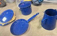 All five blue speckled enamel cookware pieces laid out