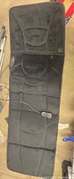 Full view of black massage pad showing entire length, remote and power cord attached