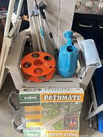 Group view showing boxed Pathmate mold, blue watering can, tripod sprinkler, orange hose reel pieces