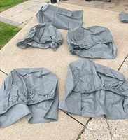 Five gray covers spread out on pavement