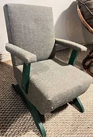 Front three-quarter view of gray upholstered rocking chair on green wood base