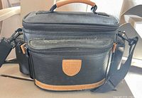 Front view of black camera bag with tan trim and handle