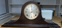 Front view of full tambour mantel clock showing wooden case and dial