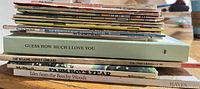 Stack of assorted books showing spines including Guess How Much I Love You and Sesame Street Library