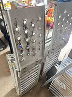 Two folded aluminum loading ramps standing vertically showing perforated surfaces and wear