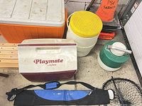 Group shot showing Igloo Playmate cooler, orange chest cooler, white beverage cooler with yellow lid, green jug, rod bag, fishing net