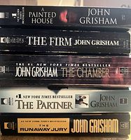 Stack view of all five John Grisham paperbacks showing spines and titles