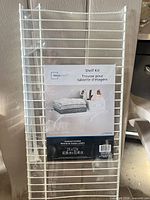Front view of sealed Mainstays shelf kit showing full wire shelf and packaging label