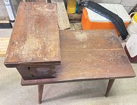 full view of telephone table showing two tiers, tapered legs, carved side panel