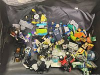 Top view of loose LEGO and compatible pieces showing minifigure parts, vehicle sections, TARDIS panel