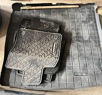 Stacked floor mats on top of cargo liner; shows pattern, MuddyBuddy logo