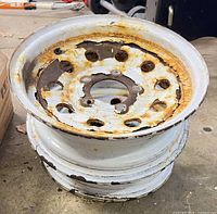 First wheel angled on floor showing full rim, rust patches, 6 lug holes