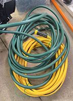 Coiled green and yellow heavy-duty hoses showing overall condition and connectors