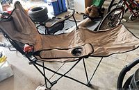 Full view of unfolded tan folding camp chair in garage setting