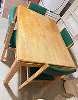 Rectangular light oak table with four green vinyl chairs