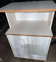Front angled view of white cabinet showing doors, shelf and casters