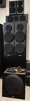 Full set stacked: two towers, two small speakers on top, subwoofer at base, cables visible