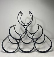 Front view of black metal wine rack showing six semi-circular bottle cradles