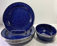 Stacked blue speckled enamel plates and bowls showing rims and finish