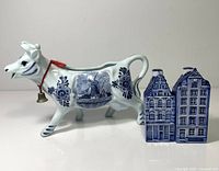 cow creamer alongside two house-shaped shakers
