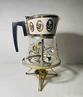 Full view of glass carafe on brass warming stand