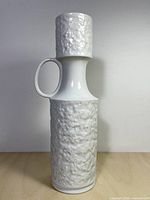 Full front view of tall white textured KPM vase with handle