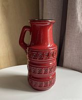 Angled left-front view of red Scheurich vase showing relief pattern and handle