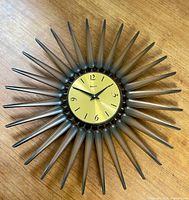 Full view of sunburst wall clock on wood surface