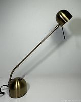 Full view of brass adjustable desk lamp showing arm, base, shade