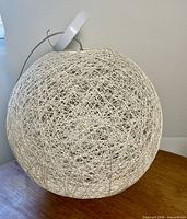 Full view of woven string globe lamp resting on table