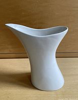 Front angled view of white sculptural pitcher on wood surface