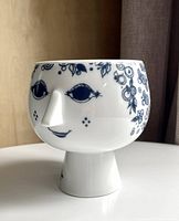 Front angle of ceramic face planter showing blue facial and floral graphics