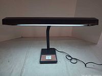 Full view of lamp illuminated showing gooseneck, base, cord