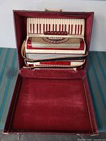 Accordion in open hard case showing keyboard, grille, interior lining