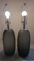 Front view of both gray smoke glass lamps illuminated showing harps and finials