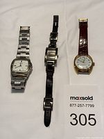 Three watches laid out: stainless Citizen, silver rectangular, gold round