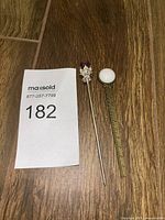 Hat pin and bookmark laid side by side with lot number card