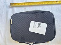 Exterior of black quilted jewelry organizer with measuring tape showing size