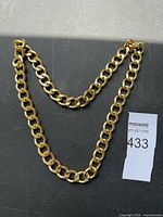 Full view of gold-tone curb chain necklace laid flat