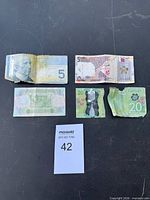 Overview of four banknotes including ripped $20, lot tag visible