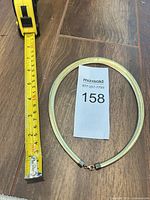 Necklace laid flat beside tape measure showing length
