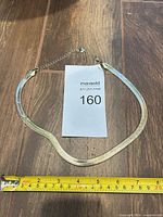 Full view of gold plated herringbone necklace with extender and measuring tape