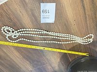 Necklace laid out full length with tape measure showing 84 inches