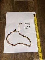 Full view of necklace laid straight with measuring tape showing length