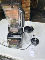 Full view of blender base, 72-oz pitcher, single-serve cup, blade assembly