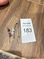 Three hair pins on wooden surface showing overall lot