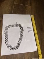 Entire necklace laid flat beside tape for scale