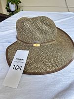 Front view of woven tan/brown wide-brim hat showing crown shape, band and trim